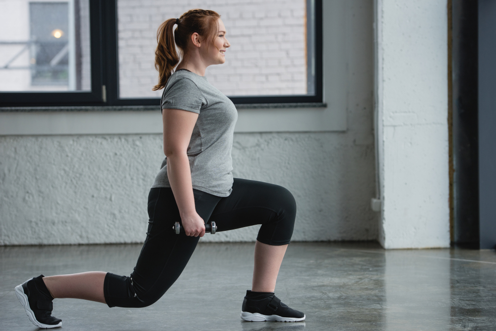 Plus-sized woman doing weight lunges to preserve muscle mass